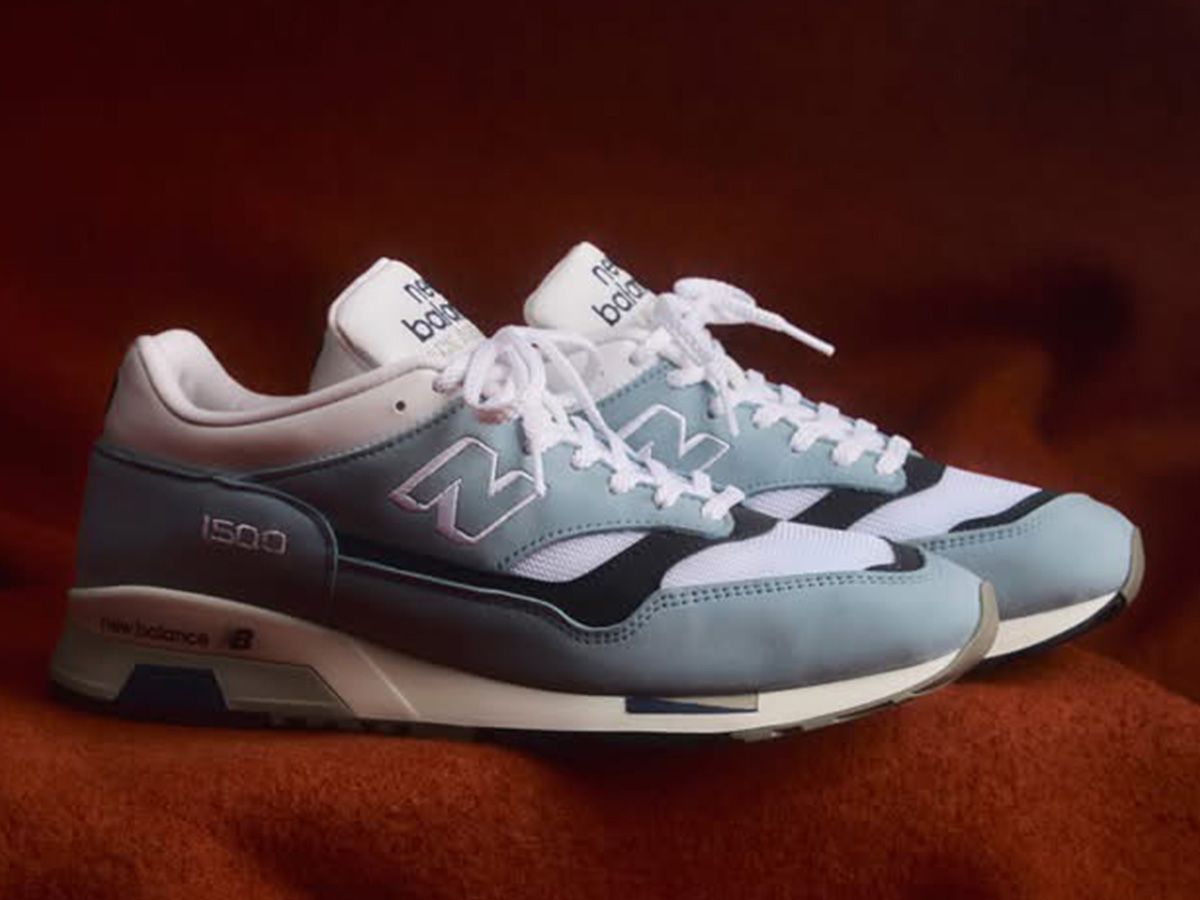 Para butów New Balance w kolorach niebieskim i białym, wyeksponowanych na czerwonym tle. - zdjęcie