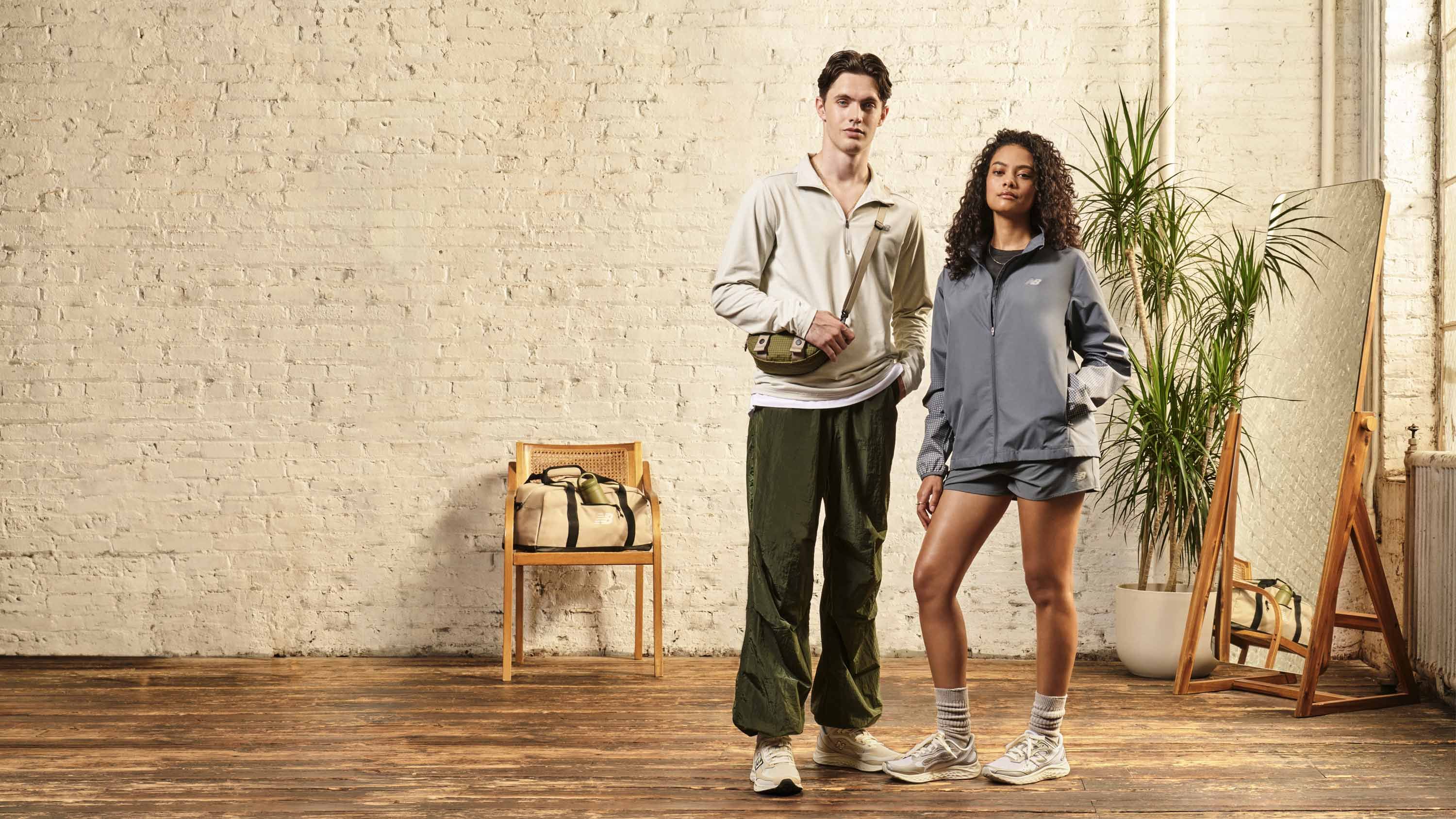 Para modeli w ubraniach New Balance na tle ceglanej ściany.